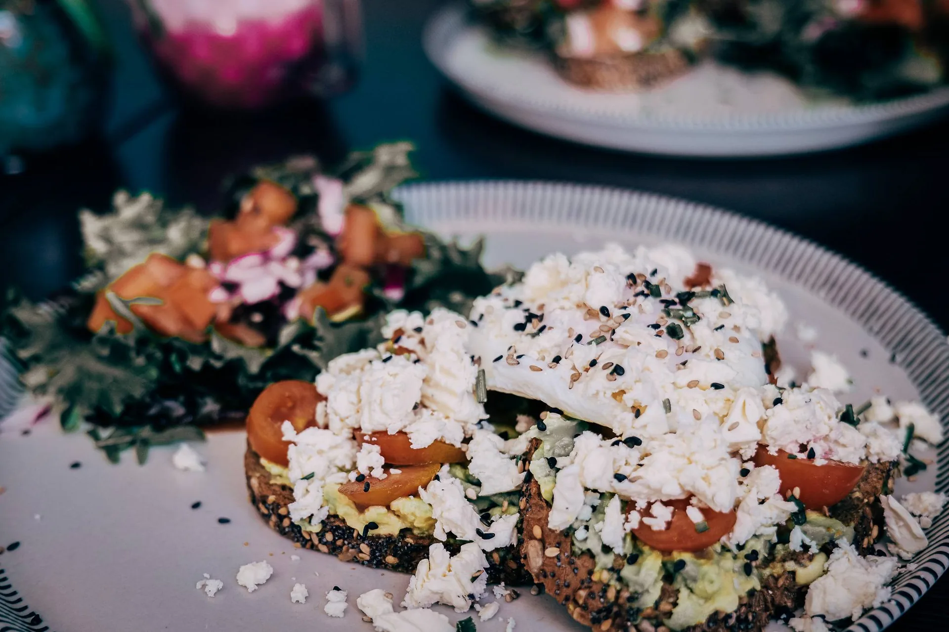 Plate of open-faced sandwiches topped with fresh cheese, tomatoes, and seeds, served with a green salad, at Goji restaurant in Lagos, Algarve.