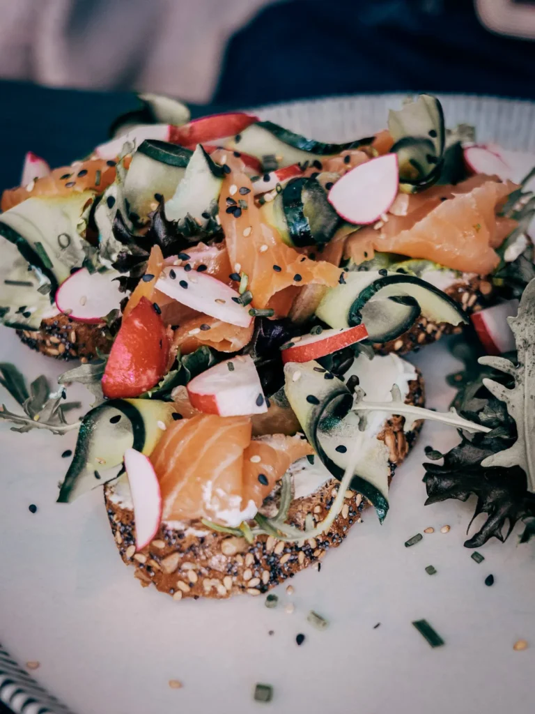 Seeded bread toasts topped with smoked salmon, cucumber, radish, bell pepper, and sesame seeds, served at Goji restaurant in Lagos, Algarve.