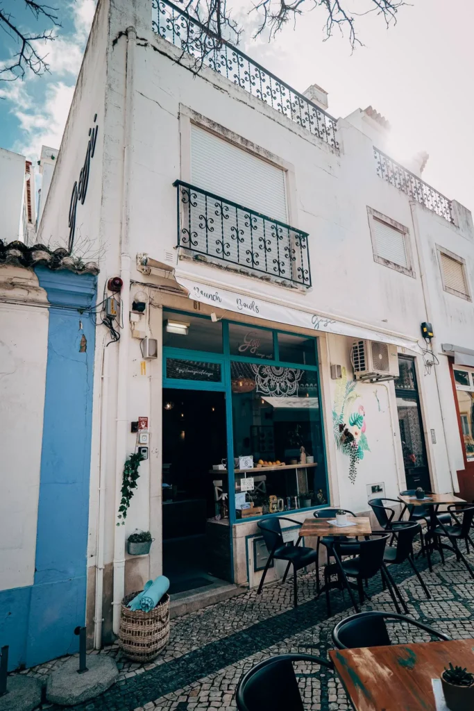 Facade of the Goji restaurant in Lagos, Algarve, with an empty outdoor terrace and Mediterranean decor under a partially cloudy sky.