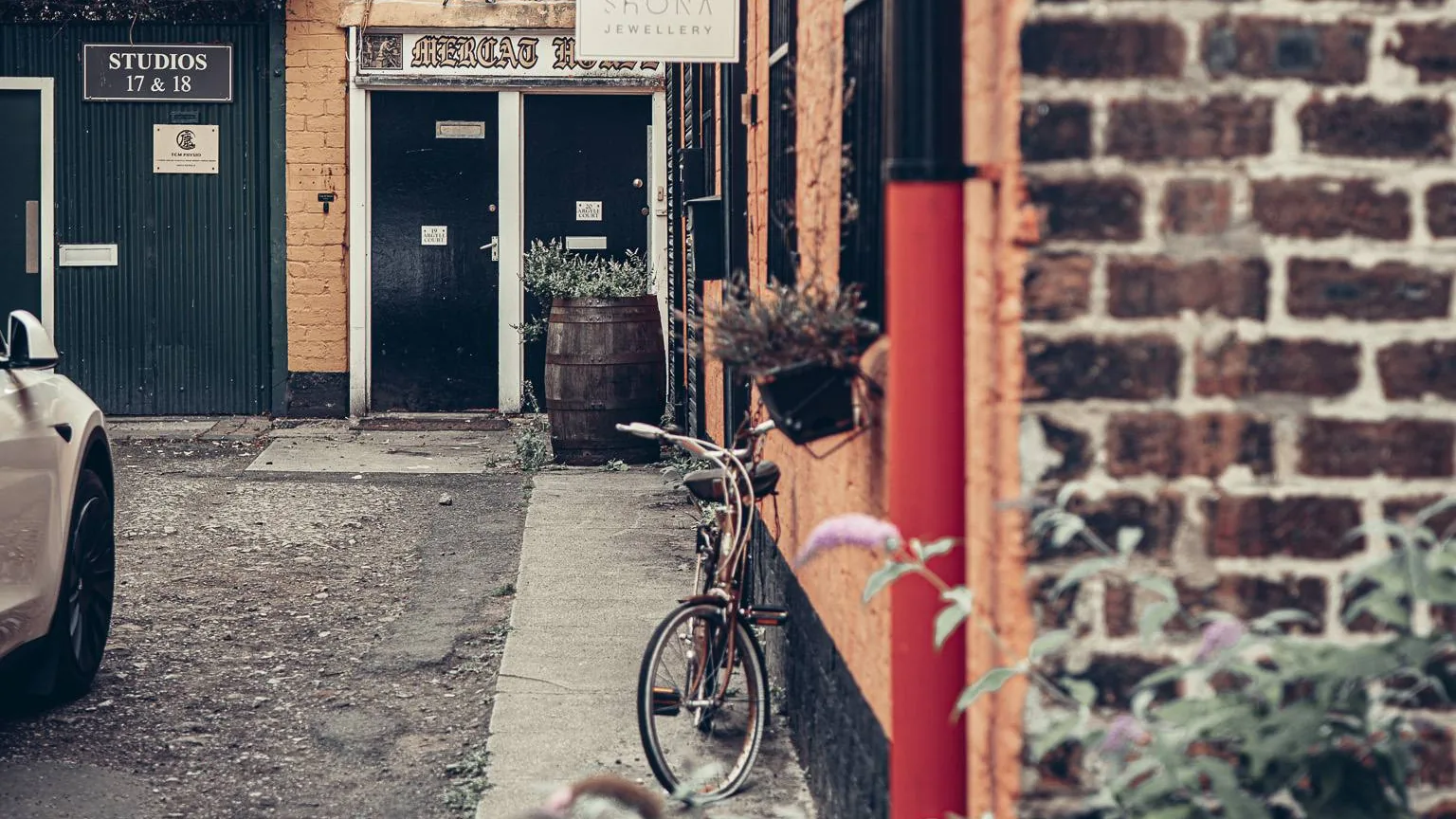 The Hidden Lane in Glasgow, its studio signs and a car parked in the close.