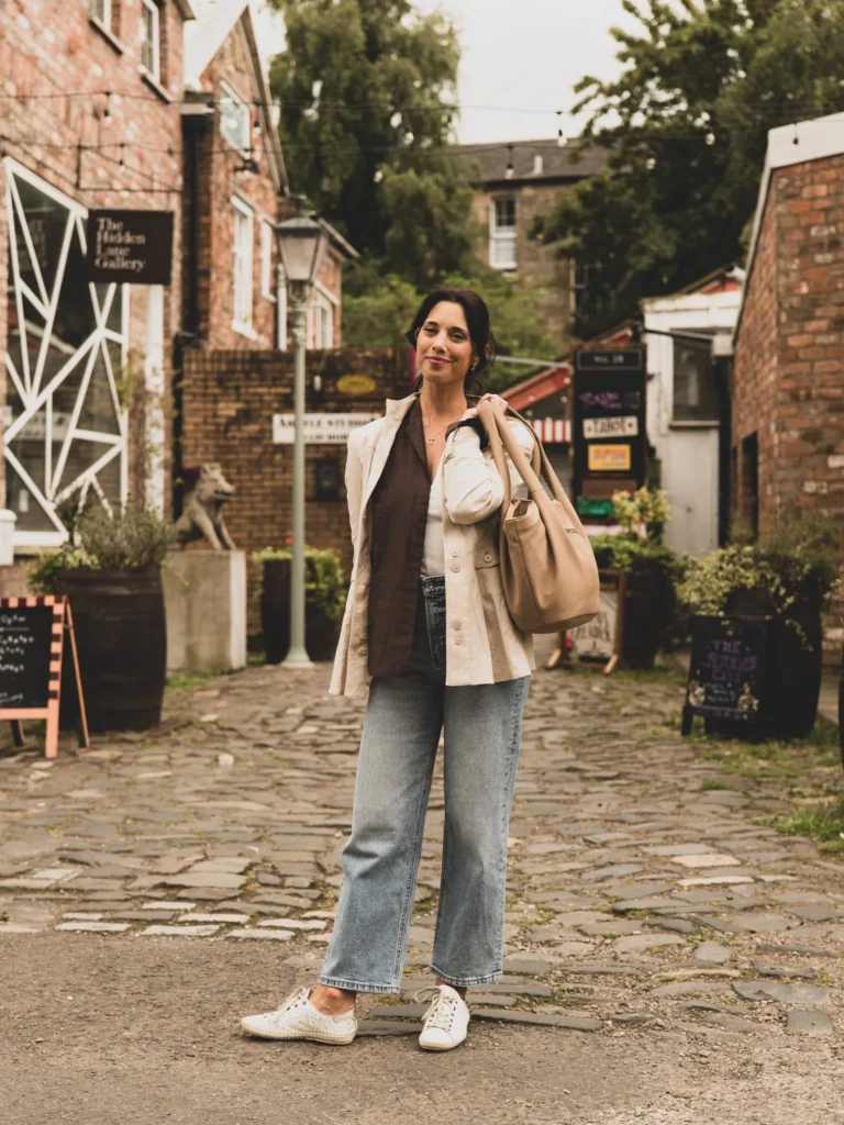 Caroline in the cobbled alley of The Hidden Lane, in Glasgow, between the brick facades, in soft natural light.
