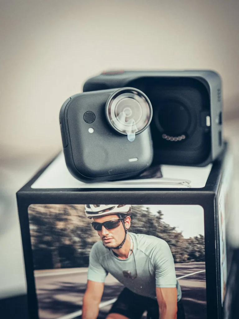 The Insta360 GO Ultra camera module in front of its Action Pod, with the magnetic cradle of the case clearly visible.