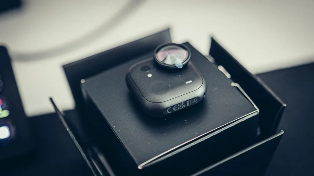 The Insta360 GO Ultra camera module in matte black, sitting in its box at unboxing, with the protective film still on the lens.