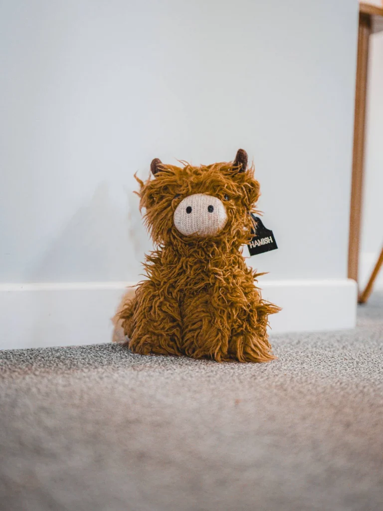 Highland cow plush toy placed on a carpet in an interior at Rocklee Bnb, Glencoe, in the Scottish Highlands in August 2026.