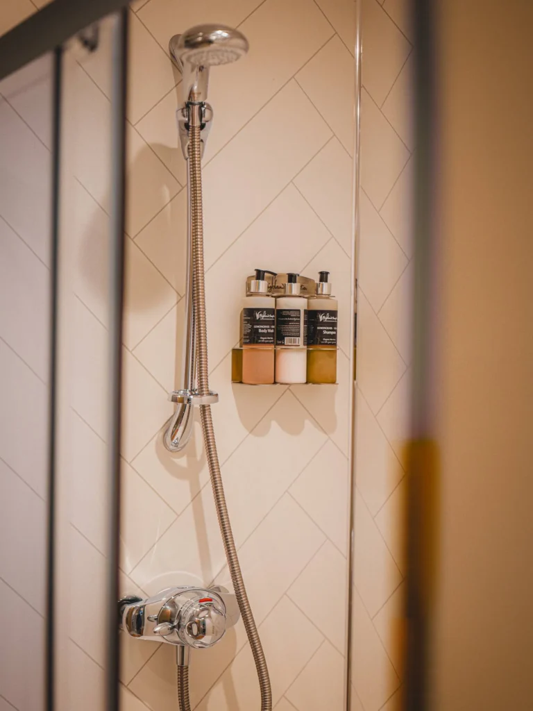 Modern shower with light tiles and toiletries in a bathroom of Rocklee Bnb in Glencoe, Highlands, Scotland.