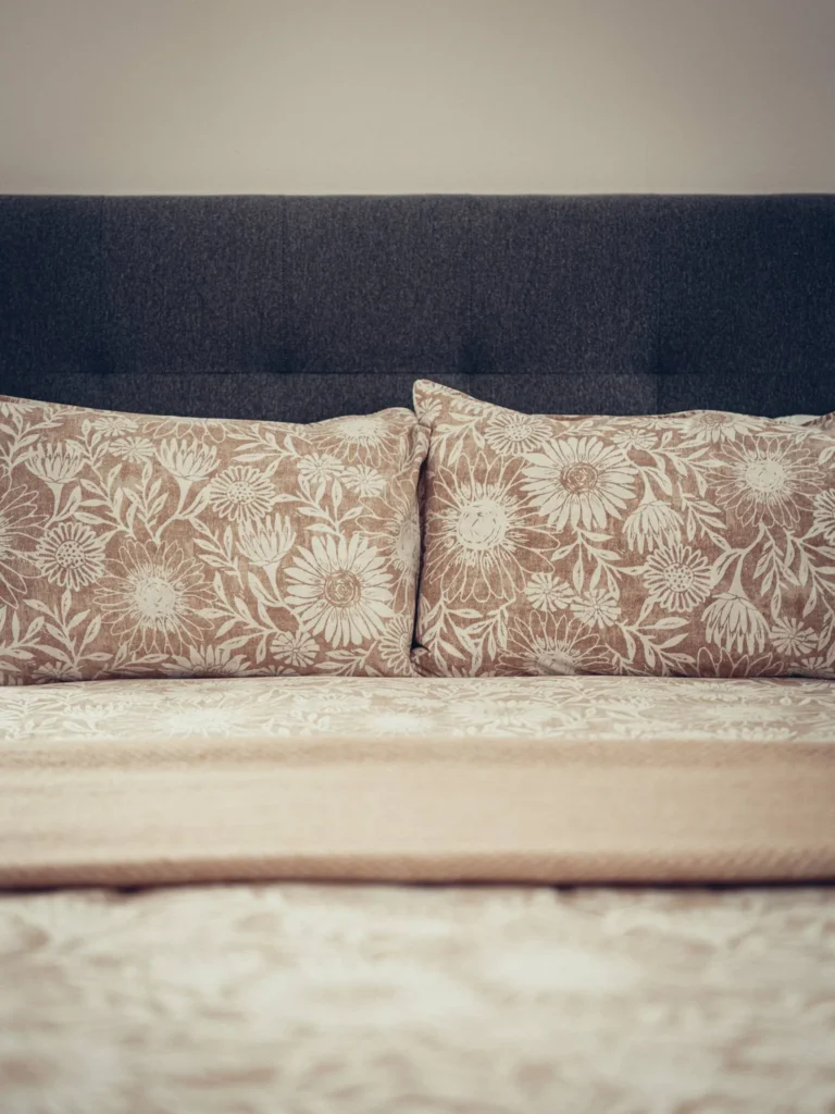 Double bed carefully made with a grey headboard and floral patterned cushions, in a room at Rocklee Bnb in Glencoe in the Scottish Highlands in August 2026.