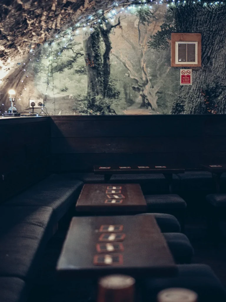 Bench corner in dim light under a stone arch at the Settle Inn, in Stirling, wooden tables and fairy lights.