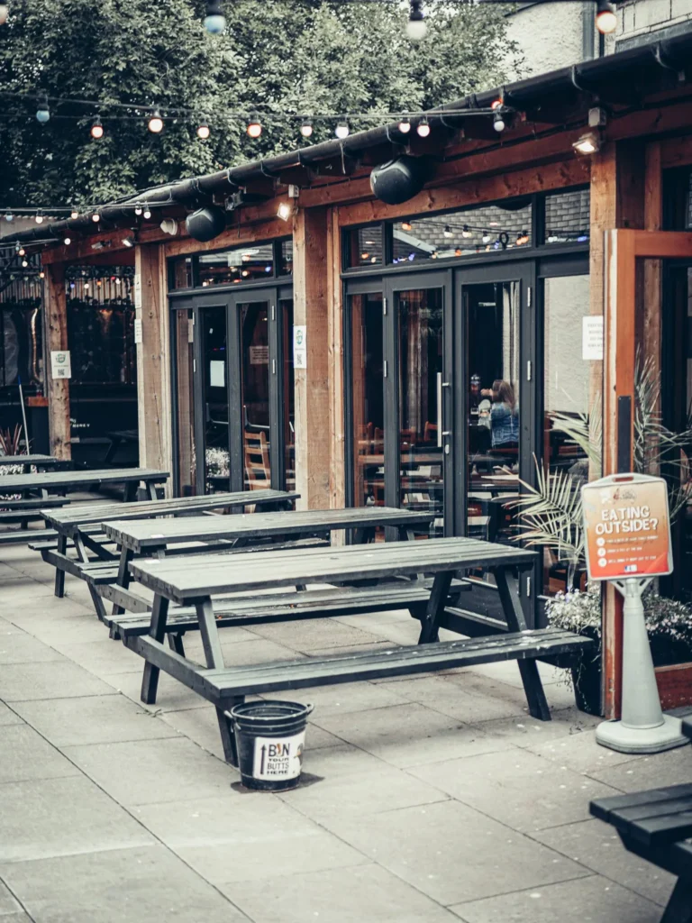The courtyard at Slanj-A-Va in Stirling with empty wooden tables, fairy lights and greenery behind, quiet on a summer afternoon.