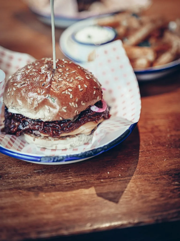 A Slanj-A-Va burger topped with crispy onions and sauce, served on a metal plate in Stirling.