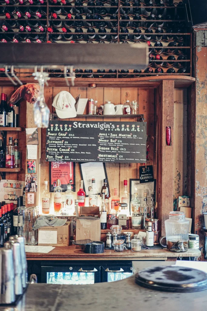 The bar counter at Stravaigin, Gibson Street in Glasgow: rows of spirits bottles, a cocktail chalkboard and a wine shelf above the wooden counter.