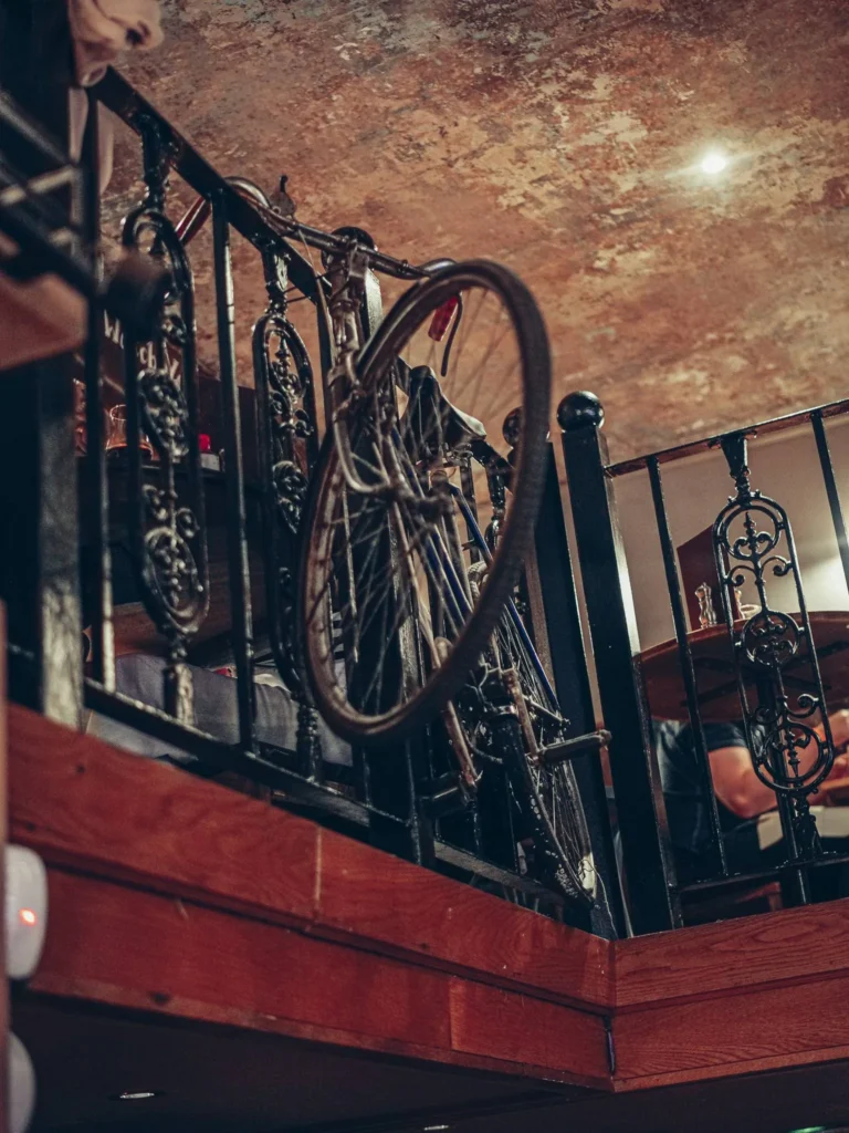 Old bicycle hanging from a wrought-iron balustrade on one of the mezzanines at Stravaigin, Glasgow: the decoration plays on salvaged objects fixed to the railings.