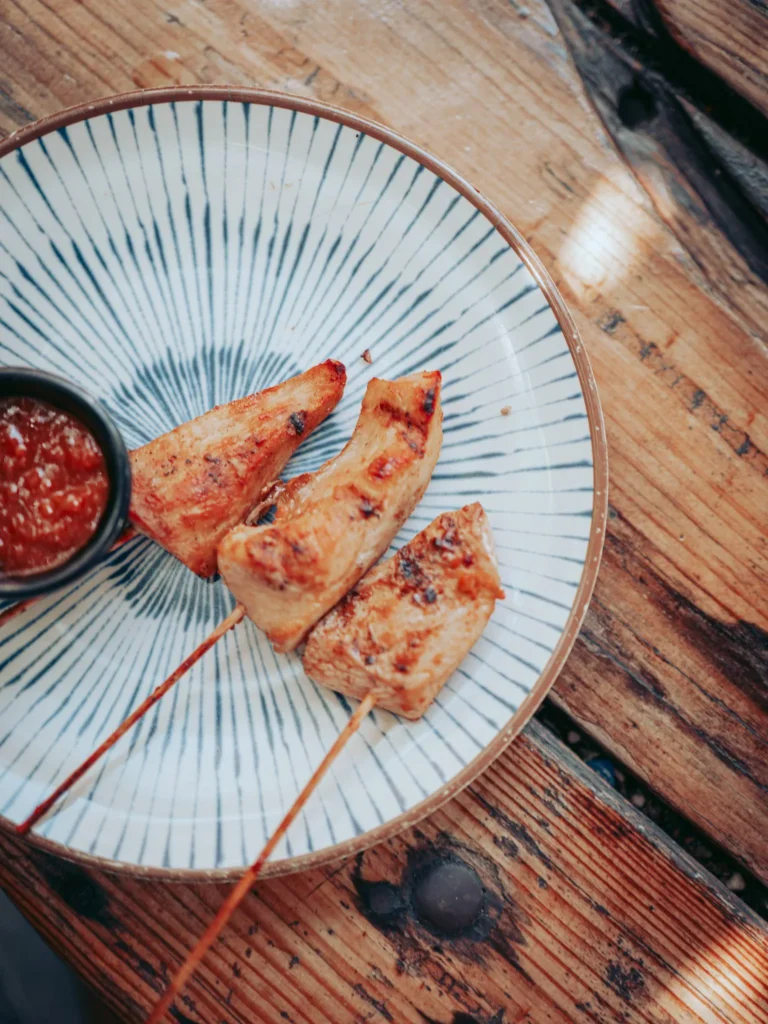 Grilled chicken skewers served with a sauce on a wooden table at The Garden Bar and Grill in Lagos.