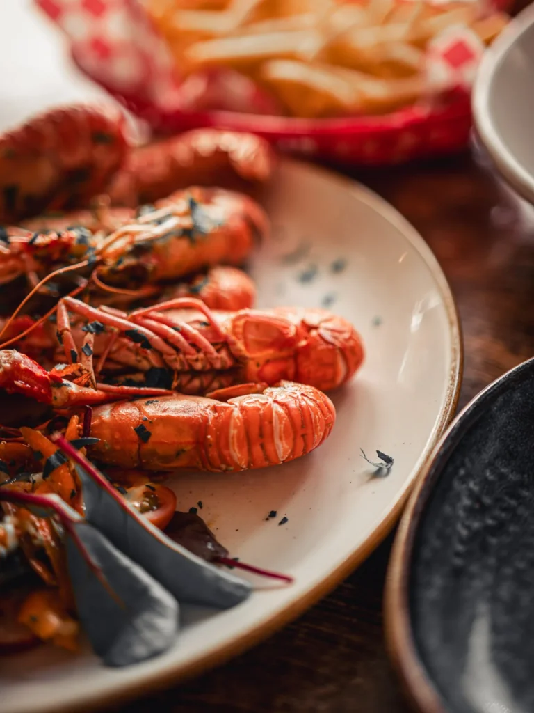 Local grilled langoustines served with salad and fries on a wooden table at The Geographer in Fort William.