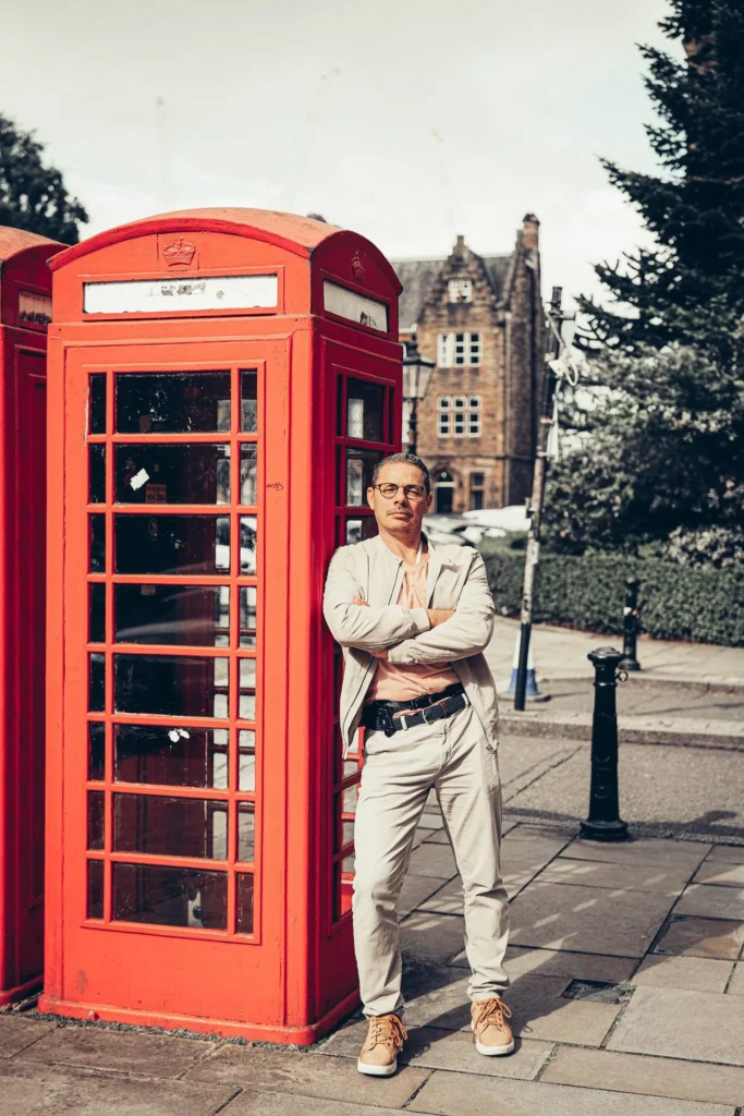 Xavier in front of a red phone box, the neo-Gothic facade of the University of Glasgow in the background.