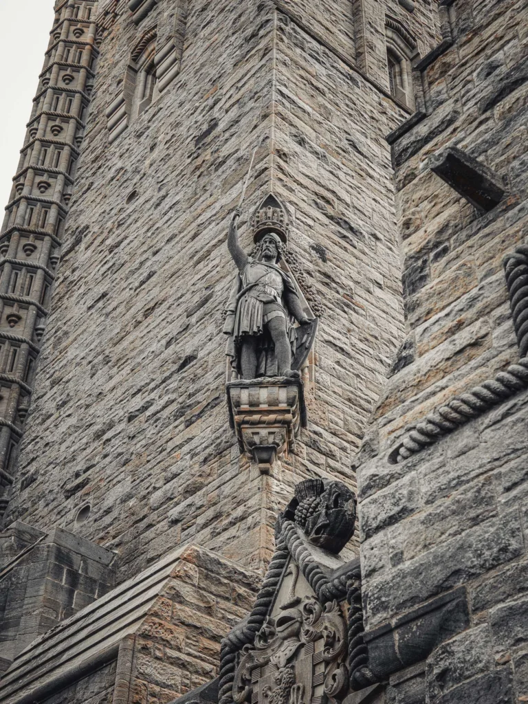 Architectural detail of the Wallace Monument in Stirling, showing a large stone statue on the tower's facade, taken in August 2026 in Scotland.
