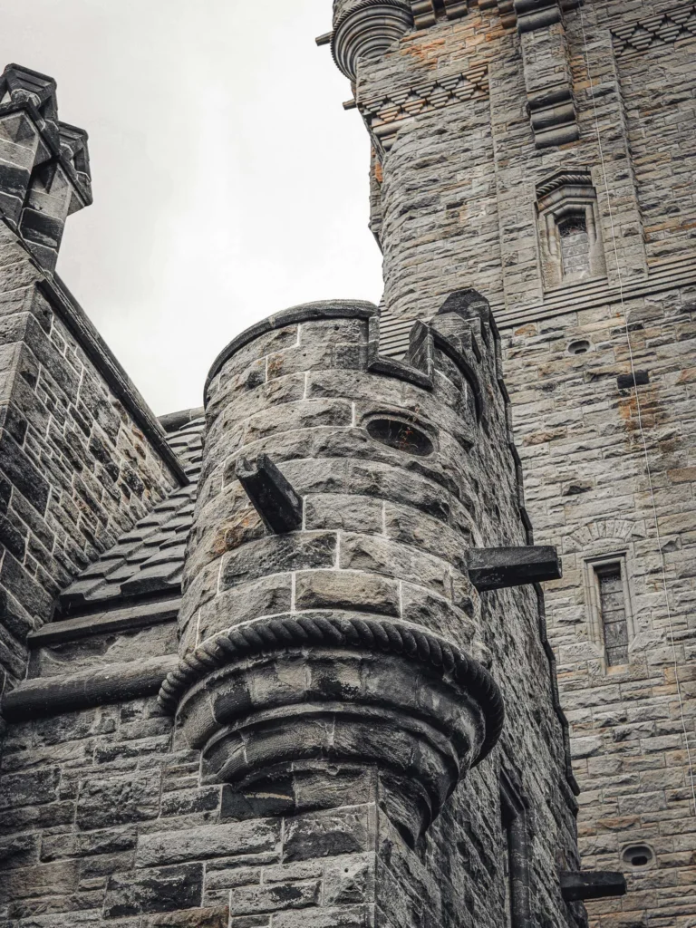 Architectural detail of the Wallace Monument in Stirling, Scotland, with its grey sandstone and Victorian Gothic carving under a cloudy sky.