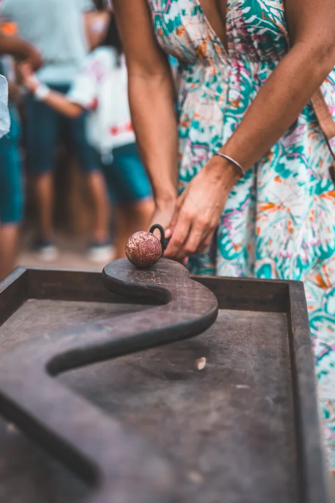 Caroline in a floral dress is participating in a wooden skill game at the medieval festival in Castro Marim, with people in the background.