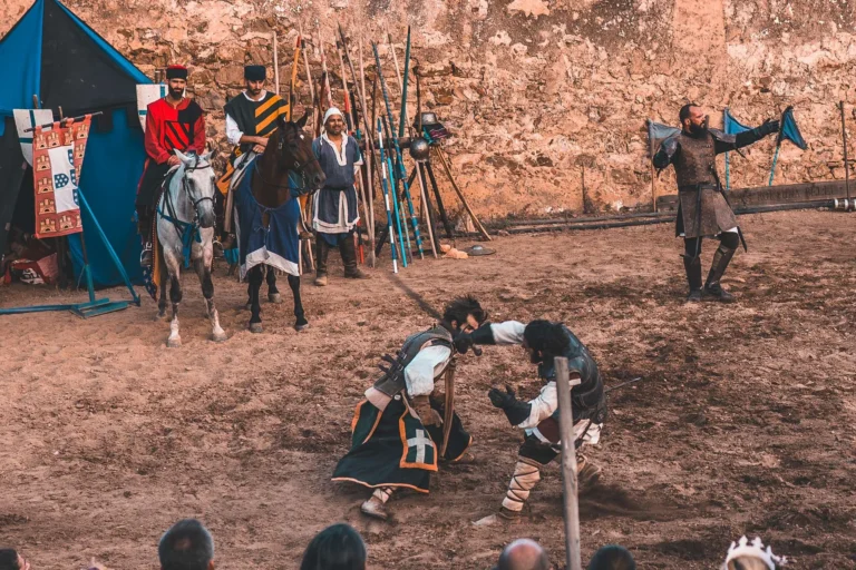 Medieval reenactment scene with people in period costumes, knights on horseback, and a simulated fight in front of an audience during the medieval festival in Castro Marim in the Algarve.