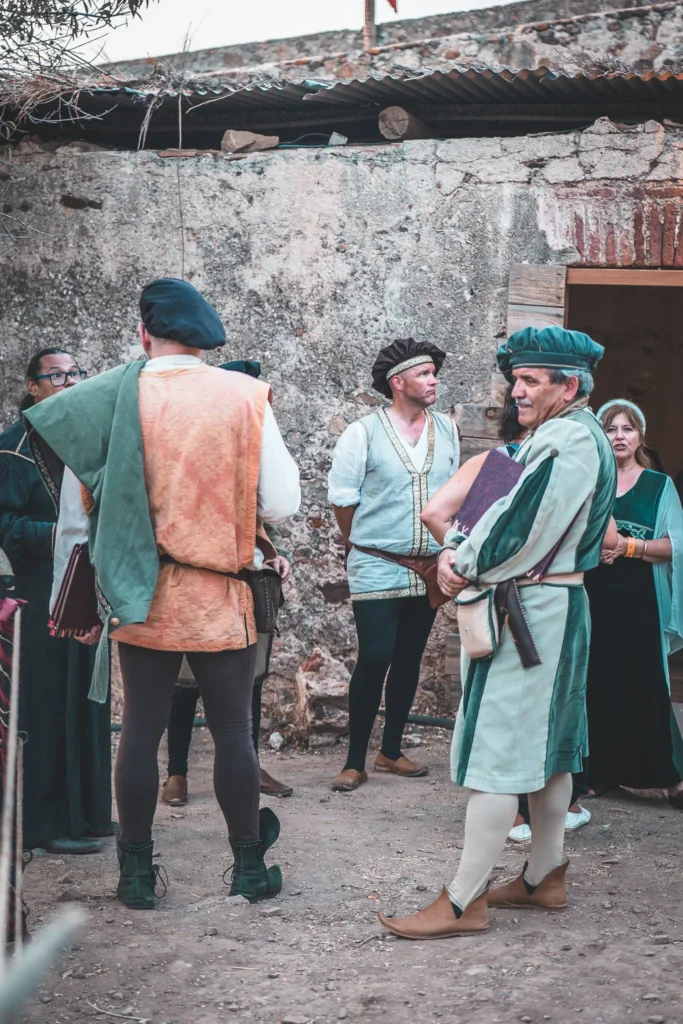 Participants in medieval costumes discuss in a stone courtyard during the medieval festival of Castro Marim in the Algarve, Portugal.
