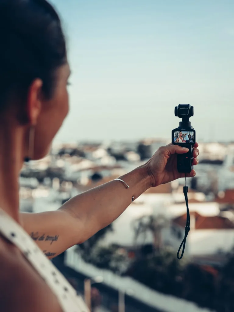 Insta360 Luna Pro held at arm's length outdoors for self-recording, screen facing towards oneself