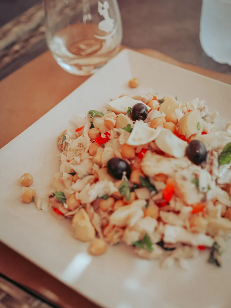Portuguese salad plate made with chickpeas, cod, black olives, and vegetables, served on a restaurant table in Tavira, Algarve.