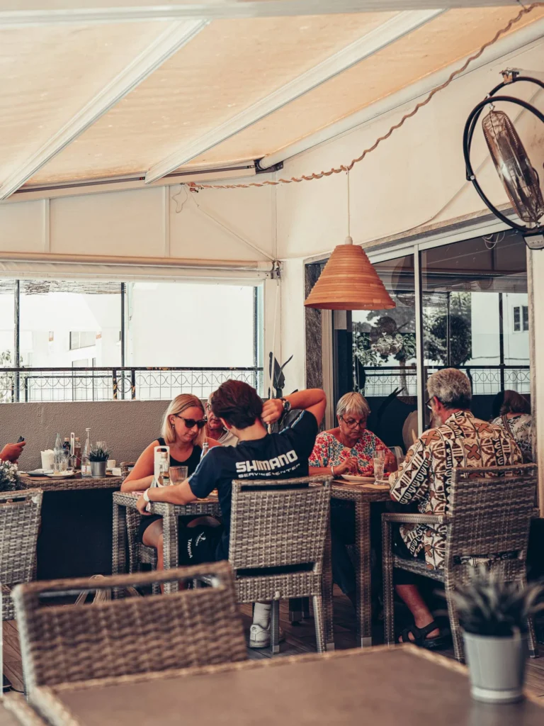 Group of people seated at a table in the veranda of a restaurant in Tavira, summer and relaxed atmosphere.