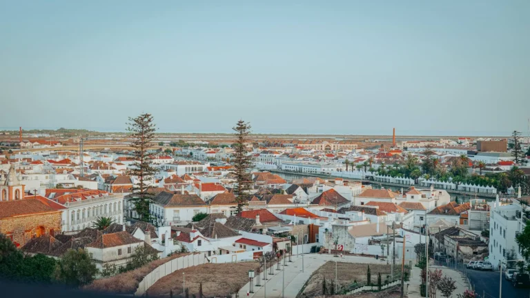 View from the terrace of the Nomad, rooftop of Maria Nova in Tavira, over the rooftops of the city and the Ria Formosa that opens towards the ocean at the end of the day.