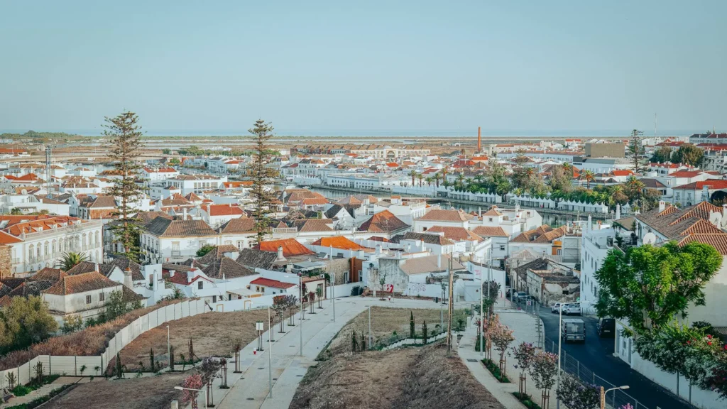 Panorama of the red and white rooftops of Tavira from the terrace of Nomad, ocean side, under a clear sky.
