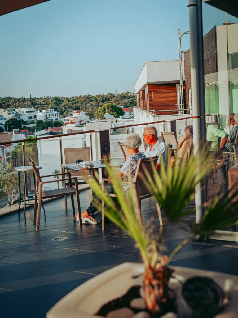 The outdoor terrace of the Nomad, which almost wraps around the rooftop of Maria Nova in Tavira: tables occupied at the end of the day, clear view of the city and the vegetation.