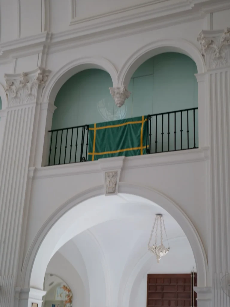 Green hanging with yellow trim folded over a gallery railing in El Rocío sanctuary