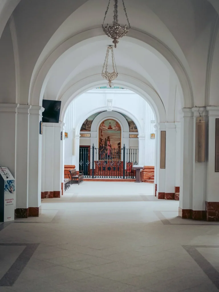 White arches and hanging lights in a side aisle of El Rocío sanctuary