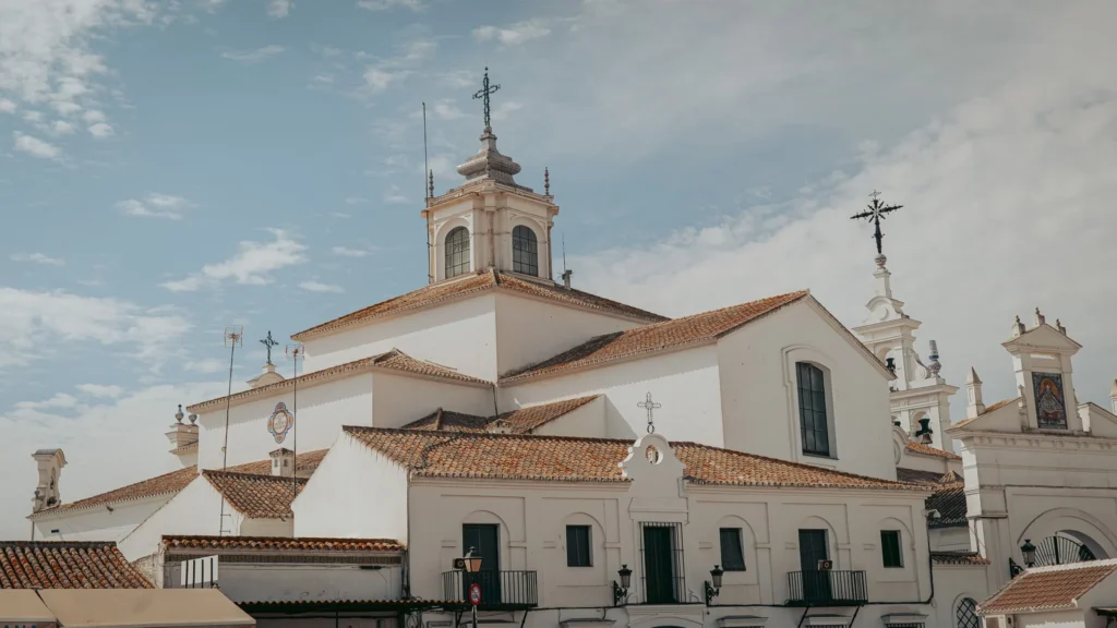 Side view of El Rocío sanctuary with white walls, tiled roofs and bells